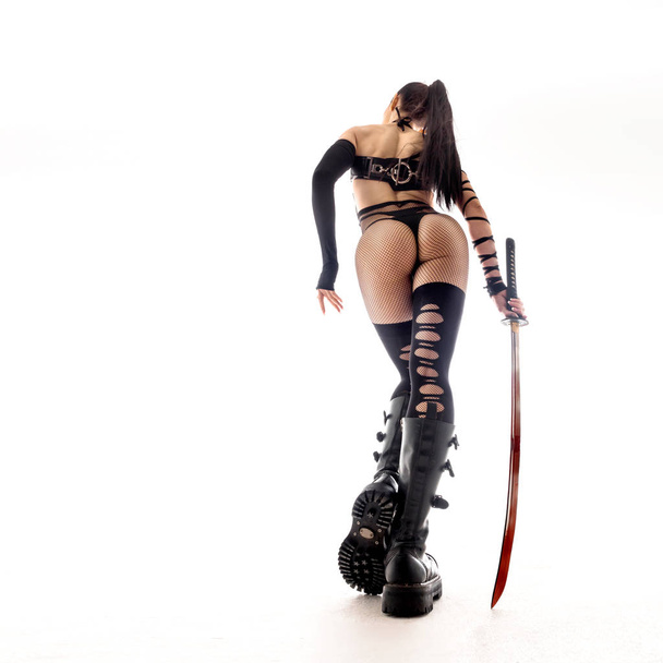 Sexy woman in anime uniform witha a katana sword. ciew from back. - Photo, Image