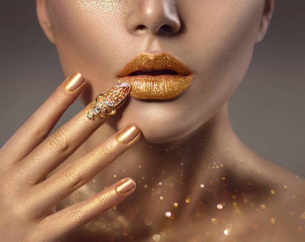 Woman with golden makeup and golden nail accessory on finger - Fotografie, Obrázek