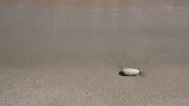 Oceaan golven lappen op een gouden strand met een kiezelsteen onder zonnige hemel high definition film. - Video