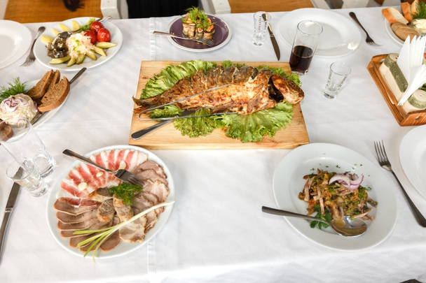 Gebakken vis en gerechten op een feestzaal tafel in een restaurant - Foto, afbeelding