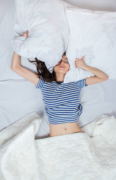 Młoda kobieta piękna, budząc w pokoju światło. Zrelaksowany kobietę leżącą w łóżku w sleepwear. - Zdjęcie, obraz