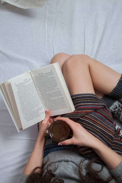 . Mujer relajada acostada en la cama y leyendo un libro
.  - Foto, imagen