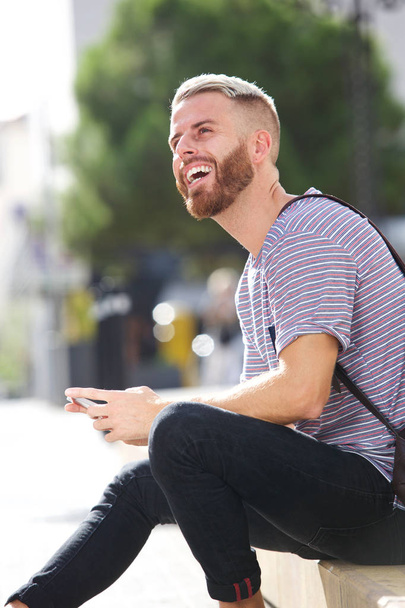 Dışarıda hareket eden telefon ile gülümseyen erkek üniversite öğrencisi portresi - Fotoğraf, Görsel