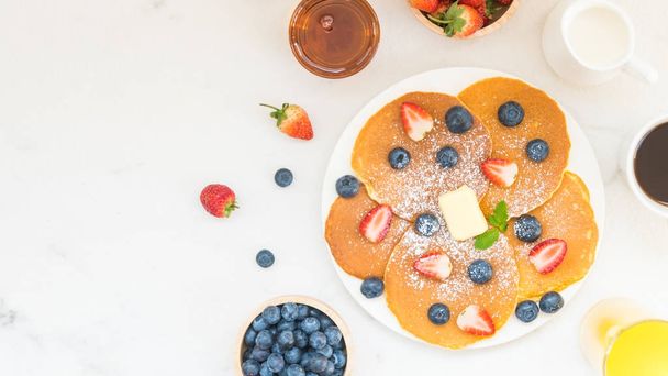 Здоровий сніданок набір з чорницею та полуничними фруктами та чорною кавою, молоко та апельсиновий сік на фоні білого кам'яного столу
 - Фото, зображення