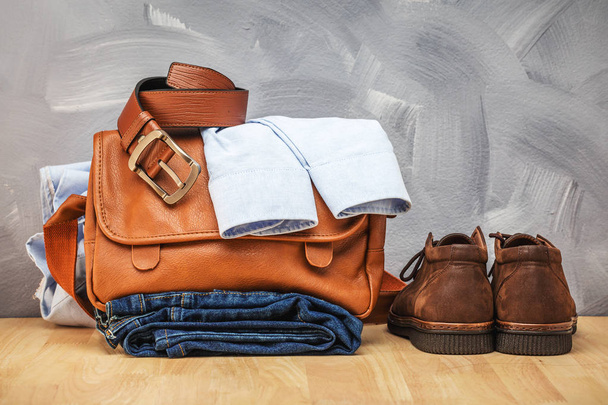 Asian vintage style men clothing and jeans and bag put on wooden table and loft concrete wall texture background. - Photo, Image