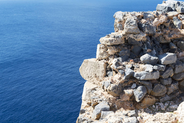 View of blue sea and sky from hole in old stonewall wall. - Φωτογραφία, εικόνα
