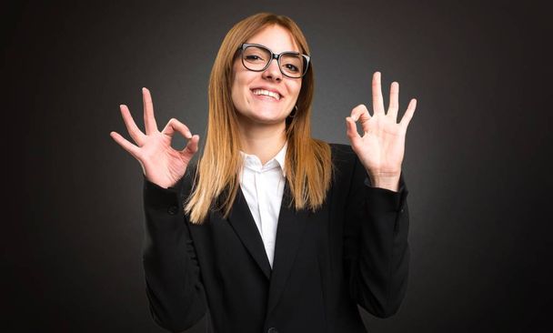 Young business woman making OK sign on dark background - Photo, Image