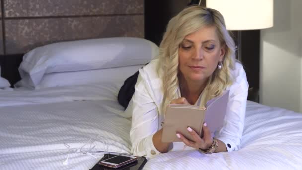 Business woman is lying on the couch and writing in a notebook - Video
