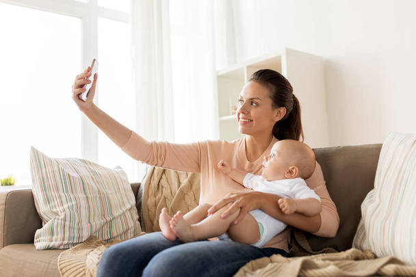 happy mother with baby boy taking selfie at home - Fotó, kép