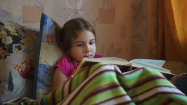 girl lying on sofa and reading a book - Záběry, video