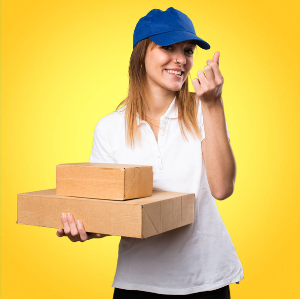 Delivery woman making money gesture on colorful background - Φωτογραφία, εικόνα