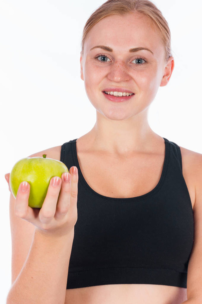 Young smiling girl with a green apple in her hand - Фото, изображение