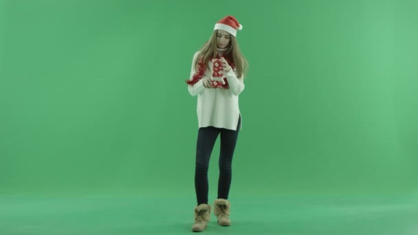 Charmante jeune femme en chapeau de Noël essaie de trouver ce qui se trouve dans son cadeau de Noël, clé chromatique sur fond
 - Séquence, vidéo
