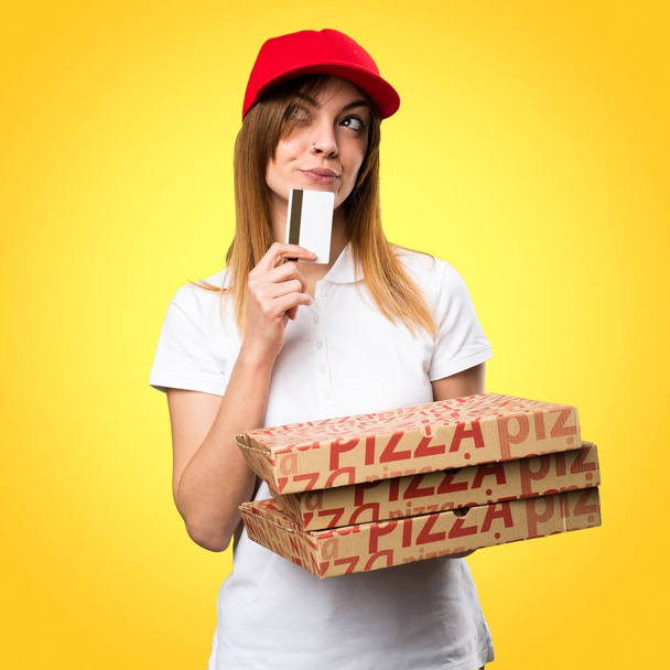 Pizza delivery woman holding a credit card on colorful backgroun - Photo, Image