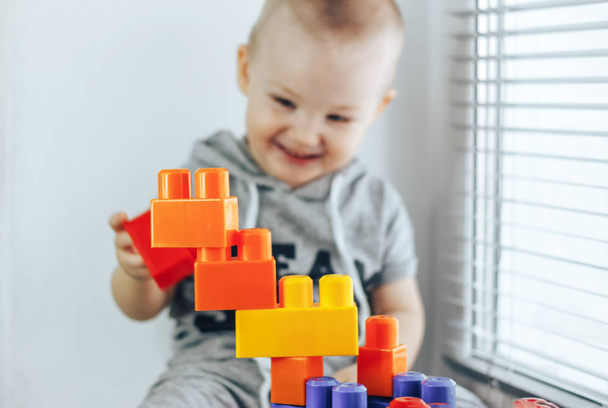 child making toy bricks. toy tower. Happy baby boy. Focus on toys. baby unfocused - Photo, Image