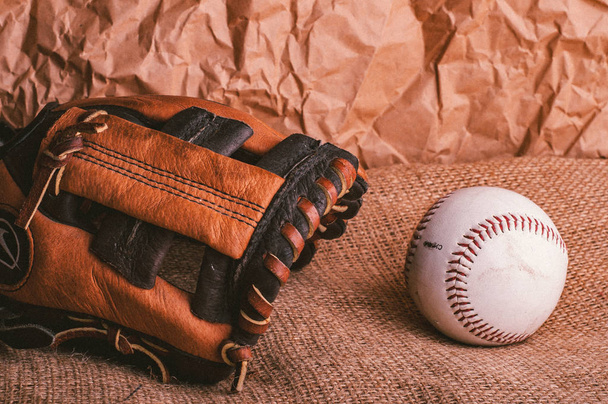 close up of american baseball hardball and of brown catchers glove on burlap texture - Фото, изображение