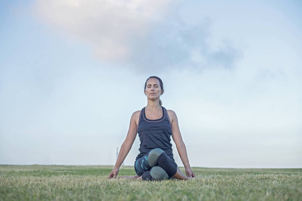 A Young woman doing yoga exercise outdoor - 写真・画像
