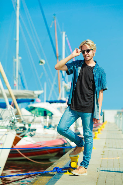 Blonde man standing near harbor in summer - 写真・画像