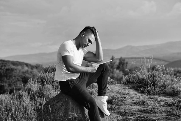 Pensive muscular man with laptop outdoor - Фото, изображение