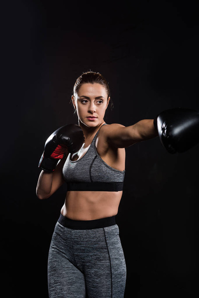 sporty athletic young woman boxing isolated on black - Fotó, kép