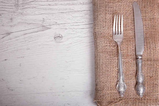 Vintage silver tableware knife and  fork is on napkin, on an old table. - Foto, afbeelding