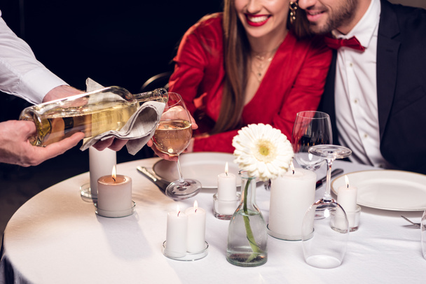 обрезанный вид официанта наливая вино во время пары, имеющей романтическое свидание в ресторане
 - Фото, изображение