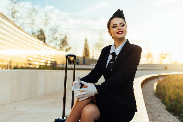 young girl stewardess with a suitcase sitting on a bench - Photo, Image