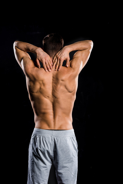 zadní pohled svalové shirtless sportovce stojící izolované na černém pozadí - Fotografie, Obrázek