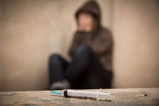 Arka planda oturan odak adam uyuşturucu bağımlısı dışarı ile şırınga - Fotoğraf, Görsel