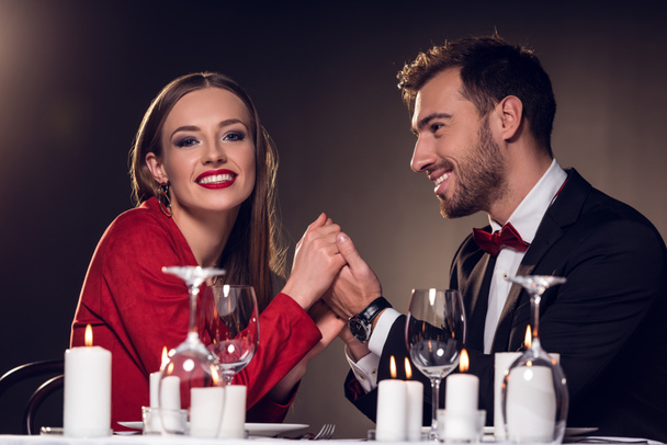 beautiful happy couple holding hands in restaurant - Photo, Image