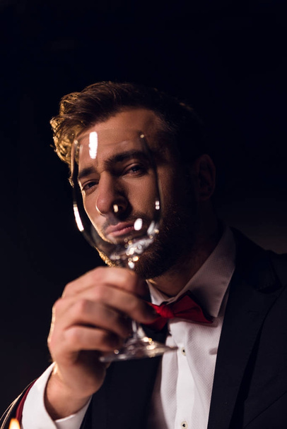 handsome bearded man looking through wine glass - Foto, afbeelding