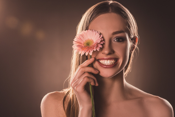 attractive cheerful girl with gerbera flower, on brown - Fotografie, Obrázek