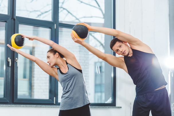 sporty young couple holding balls and training together in gym - Valokuva, kuva