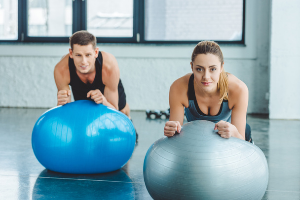 young man and woman exercising on fitness balls in gym - Foto, imagen