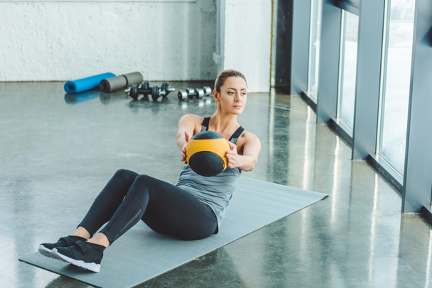 focused sportswoman doing exercises with ball in gym - Photo, Image