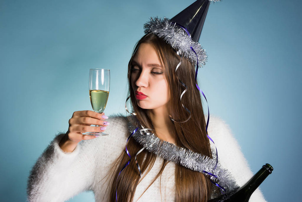 funny young drunk girl celebrates a new year alone, drinks champagne from a glass - Фото, изображение