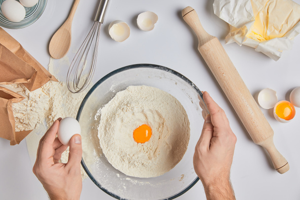 περικομμένη εικόνα του σεφ προσθέτοντας αυγά στο αλεύρι - Φωτογραφία, εικόνα
