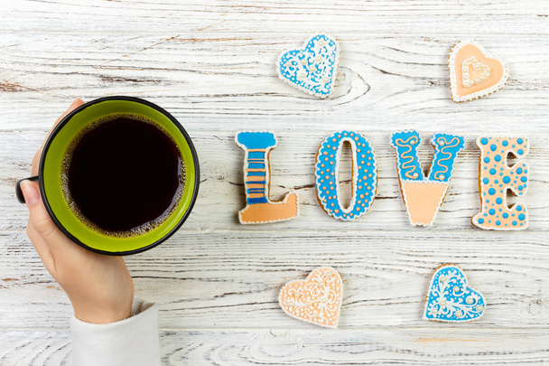 Γυναικεία χέρια με καφέ και καρδιά σχήμα cookies στο ξύλινο τραπέζι, το top view. Έννοια της αγάπης - Φωτογραφία, εικόνα