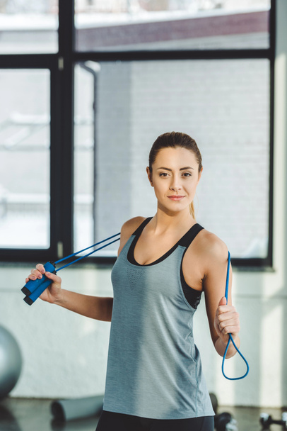 portrait of sportswoman with jumping rope looking at camera in gym - Foto, Bild