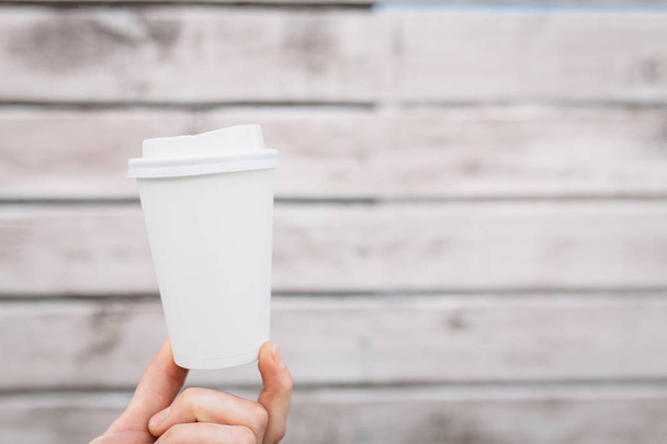 White paper or plastic Cup on the background of a wooden wall, insulated in the center, free space on the Cup - Фото, зображення