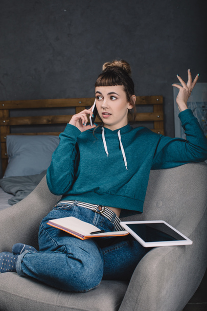 irritated girl working from home and talking by smartphone - Photo, Image