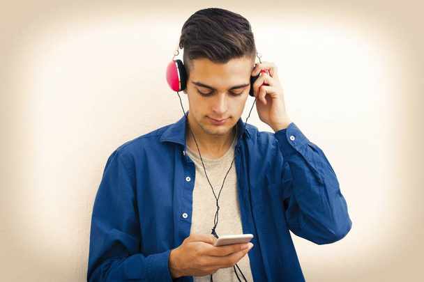 young modern teenager with phone and headphones listening to music - Foto, afbeelding