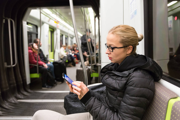Junges Mädchen liest von Handy-Bildschirm in U-Bahn. - Foto, Bild