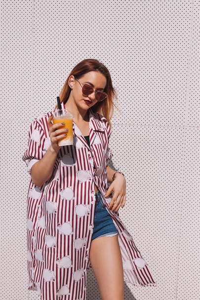 beautiful young woman in striped red shirt with mango shake in plastic cup - Zdjęcie, obraz