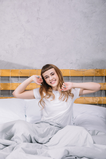 happy girl stretching in bed in morning and looking at camera - Fotoğraf, Görsel