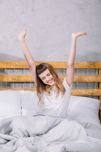 happy girl stretching in bed in morning - Photo, Image
