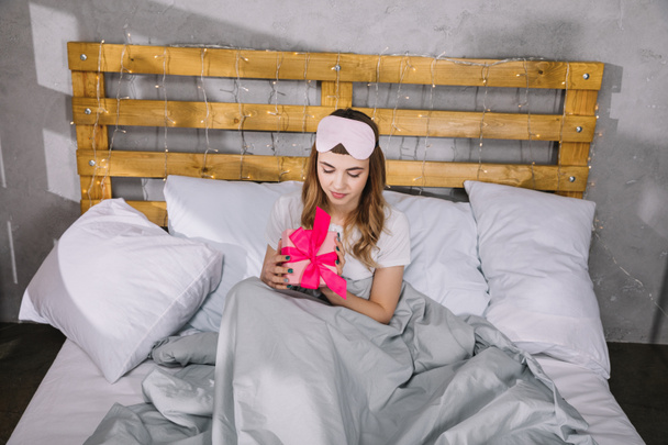 happy girl sitting in bed with present box - Photo, image