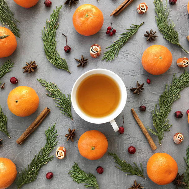 Winter background. Composition with fir branches, cinnamon, mandarins and cup of tea. Flat lay, top view. - Photo, Image