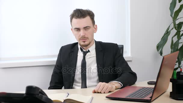 Young businessman in suit sitting in office and showing sign of silence. 60 fps - Πλάνα, βίντεο