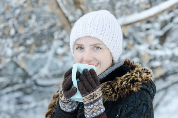 Dívka v zimě oblečení pít čaj z hrnečku. Boční pohled. Closeup - Fotografie, Obrázek